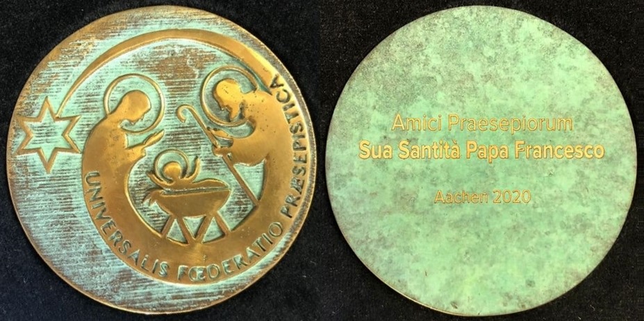 De izquierda a derecha, anverso y reverso de la medalla conmemorativa de la Concesión de la Distinción al Mérito Belenista Un.Fœ.Præ a Su Santidad el Papa Francisco durante el XXI Congreso Internacional Belenista, celebrado en Aquisgrán (Alemania) entre el 15 y el 19 de enero de 2020